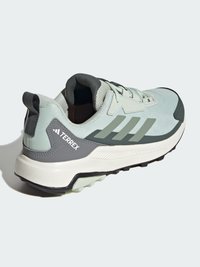 Baskets de sport vert clair avec une tige en maille, accents vert foncé et une semelle en caoutchouc durable dotée d'un profil à crampons pour l'adhérence.