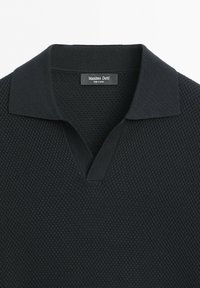 Polo en maille texturée noire avec un large col et une étiquette Massimo Dutti à l'intérieur de l'encolure.