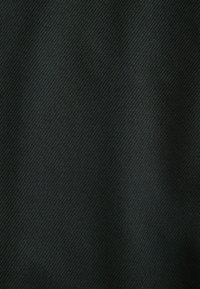 Dunkelgrüner Stoff mit glatter Textur und subtiler diagonaler Webmusterung, die ein mattes Finish und einen weichen Fall zeigt.