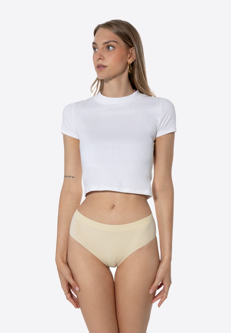 T-shirt blanc court à manches courtes associé à une lingerie taille haute beige clair. Texture lisse, design simple et silhouette ajustée.