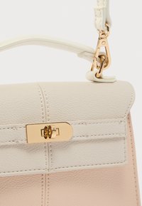 Τσάντα χειρός από ανοιχτό μπεζ δέρμα με χρυσό κούμπωμα, διαθέτει ομαλή υφή, δομημένο σχήμα και αποσπώμενο λουρί.