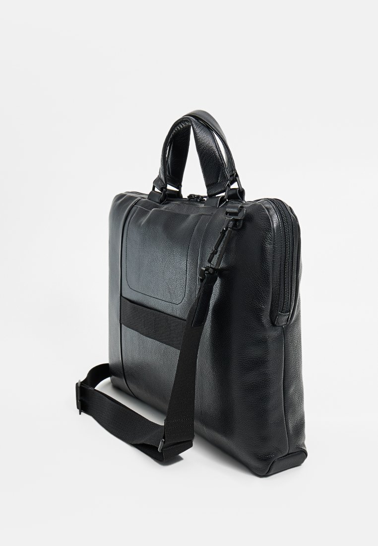 Czarna skórzana torba na laptopa z podwójnymi uchwytami i odczepianym paskiem. Posiada zamek błyskawiczny, przednią kieszeń oraz fakturowane wykończenie.