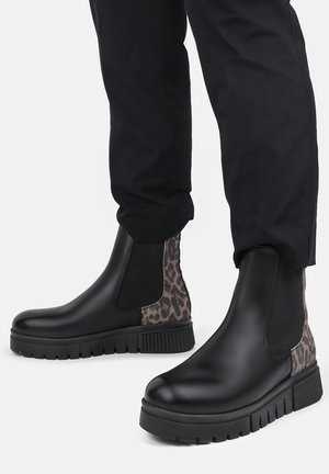 Black Chelsea boots with a chunky sole, featuring animal print side panels and elastic gussets. Smooth texture with a matte finish.