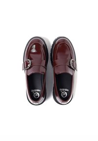 Mocassini in pelle verniciata color bordeaux con punta arrotondata, suola in gomma nera e dettaglio decorativo in metallo sulla fascia.