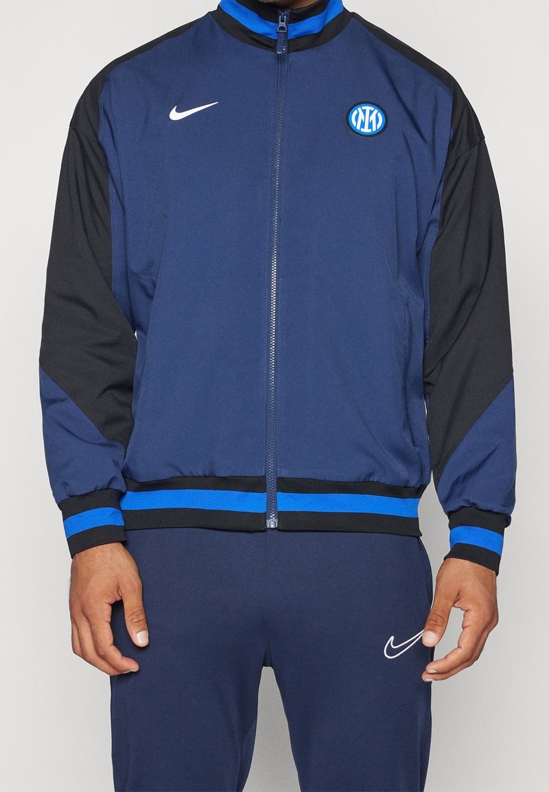 Navy blue zip-up jacket with black sleeves, featuring a blue stripe at the hem and Nike logo. Includes an Inter Milan emblem on the chest.