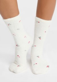 Białe, puszyste skarpetki o miękkiej fakturze, z rozsianym kwiatowym wzorem w kolorze czerwonym i szarym. Skarpetki do kostki.