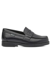 Mocasines de cuero negro con suela plana de goma, que presentan un diseño cosido y una tiras decorativa de tipo penny en la parte superior.