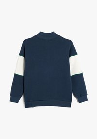 Sudadera de color azul marino oscuro con cuello alto, detalles de rayas blancas y verdes en las mangas, y puños y dobladillo acanalados. Textura de tela suave.