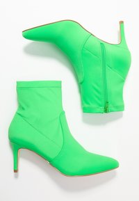 Zelené kotníkové boty vyrobené z elastického materiálu. Špičatá špička a jehlový podpatek. Obsahují boční zip a prošívané detaily na svršku.