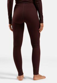 Bordeauxfarbene Leggings aus Rippstoff, mit hohem Bund, enger Passform und flachen Nähten, die barfuß getragen werden.