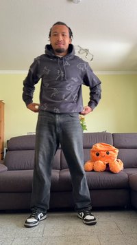 Siva pot hoodie z živalskimi in abstraktnimi vzorci, s kapuco na vrvico in kenguru žepom, se prilega s temnimi kavbojkami in črno-belimi supergami.