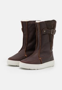 Brown leather and suede knee-high boots with white rubber soles, featuring decorative stitching and a side strap with a metal buckle.