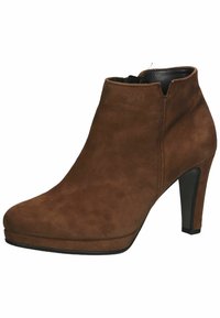 Bottine en daim marron avec un haut talon épais et une fermeture éclair sur le côté, bout rond et détails de couture subtils.