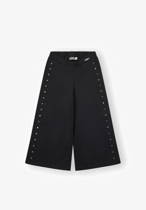 Pantalones anchos negros con detalles de ojales plateados a lo largo de los lados exteriores y una cinturilla elástica con una pequeña etiqueta de la marca.