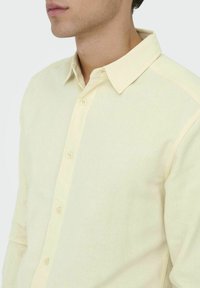 Lichtgele button-up blouse met een klassieke kraag, gemaakt van een textuurstof. Heeft een rechte snit en vier voorste knopen.