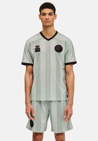 Ljusgrön sporttröja och shorts-set med geometrisk mönstring, svarta accenter och broderade logotyper. V-ringning, kort ärm.