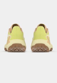 Ζευγάρι κίτρινων και μπεζ αθλητικών παπουτσιών που φαίνονται από πίσω με υφασμένα καφέ πέλματα πάνω σε λευκό φόντο.