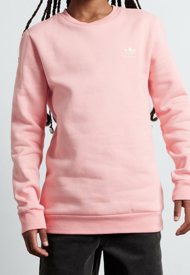 Ljusrosa sweatshirt gjord av mjuk bomullsblandning, med rund halsringning och långärmar. Märkbar vit logotyp på bröstet.