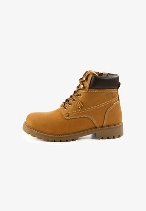 Beżowy skórzany botek do kostki z brązowymi akcentami, metalowymi przelotkami i białym przeszyciem. Posiada teksturowaną podeszwę dla lepszej przyczepności i wsparcia.