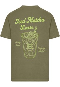 Olivengrøn t-shirt med neon grafik af en iskold matcha latte med teksten "Iced Matcha Latte," "Freshly Ground," og "Perfectly Whisked."