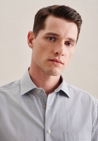 Camicia azzurra chiaro con bottoni, caratterizzata da un motivo geometrico, in tessuto di cotone, colletto a punta e chiusura con bottoni standard. Nessun logo visibile.