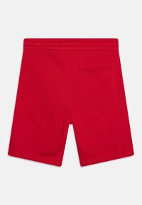 Shorts en coton rouge avec une taille élastique et une poche arrière unique. Texture lisse et design à jambe droite.