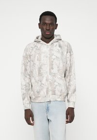 Hooded vest met rits in lichtgrijs met een natuur-geïnspireerde print. Voorzien van kangoeroezakken en geribbelde manchetten, gemaakt van zachte stof.