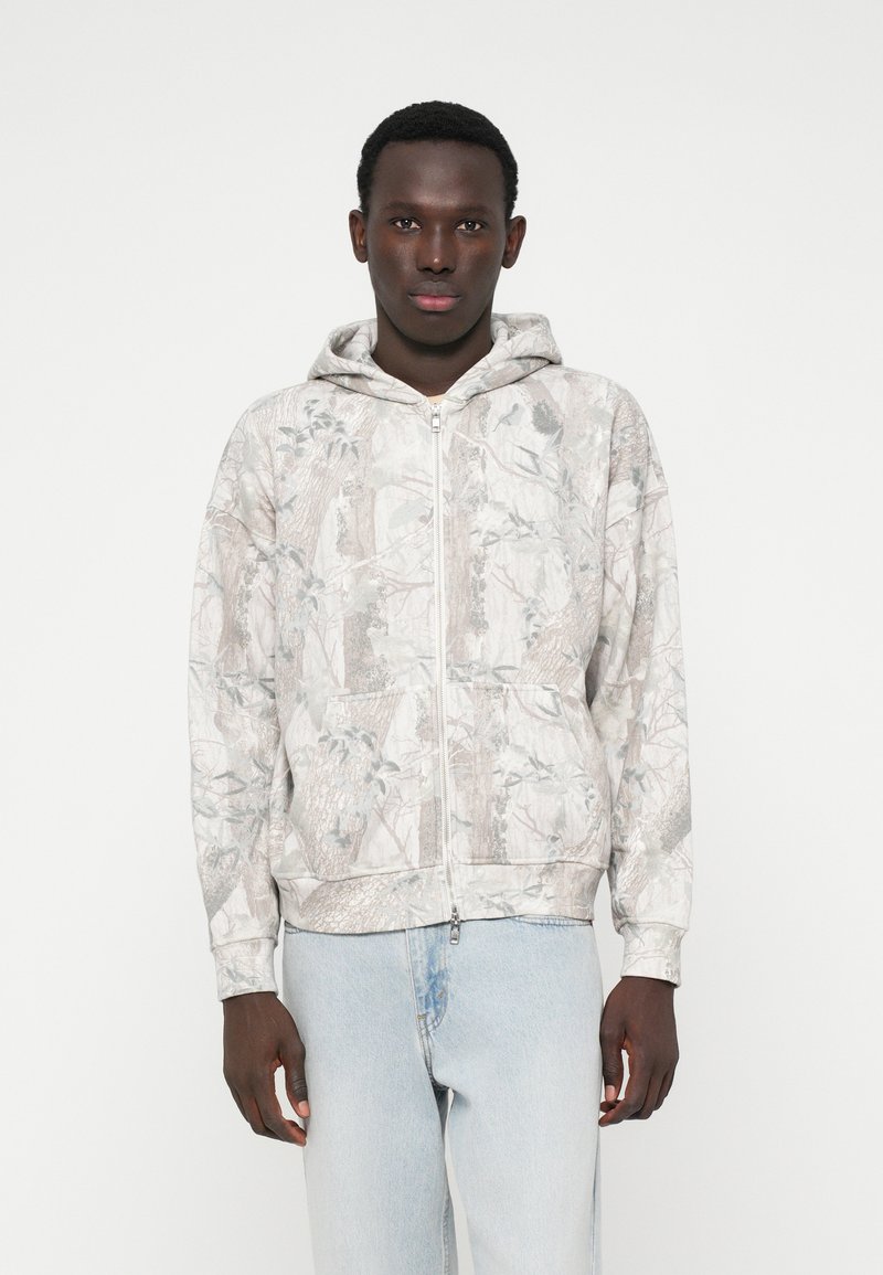 Hooded vest met rits in lichtgrijs met een natuur-geïnspireerde print. Voorzien van kangoeroezakken en geribbelde manchetten, gemaakt van zachte stof.