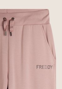 Joggers rosa chiaro realizzati in morbido tessuto, con vita regolabile, due tasche laterali e 'FREDDY' in strass sul davanti.