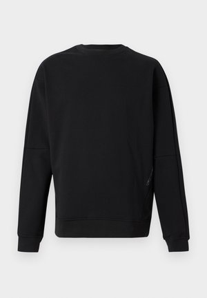 Enkel svart crewneck-genser med lange ermer, ribbede mansjetter og nederkant, vist på lys grå bakgrunn.