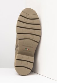 Tan ruskinds sål med et struktureret mønster, der har et logo og en detalje med det italienske flag, flad design med udtalt mønster for greb.
