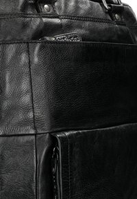 Borsa a mano in pelle nera con superficie testurizzata, cuciture evidenti e tasca con zip sul lato. Include spallacci regolabili.