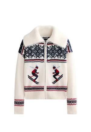 Krémový sveter so zipsovým zapínaním, zdobený motívom lyžovania a geometrickými vzormi v námorníckej modrej a červenej farbe. Hrubá pletená textúra s mäkkým golierom.
