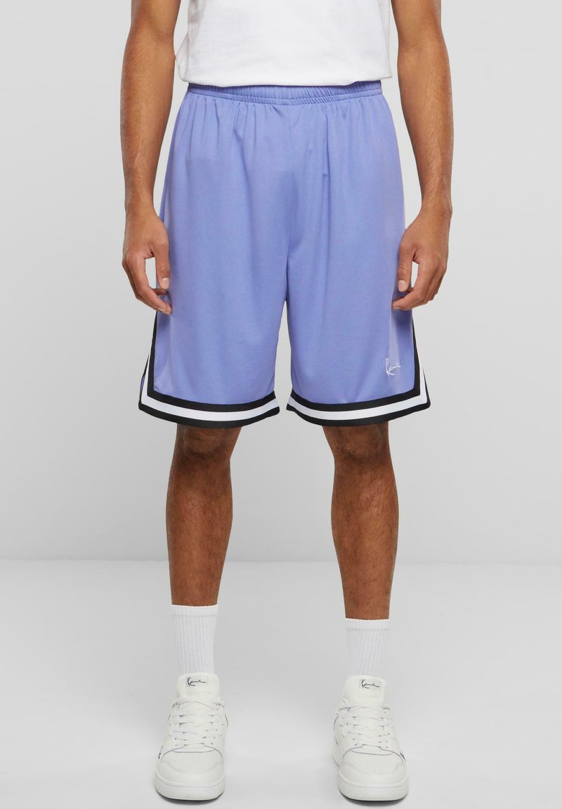 Shorts de sport violets clairs avec un ourlet rayé noir et blanc, une taille élastique et des fentes sur les côtés pour faciliter le mouvement.