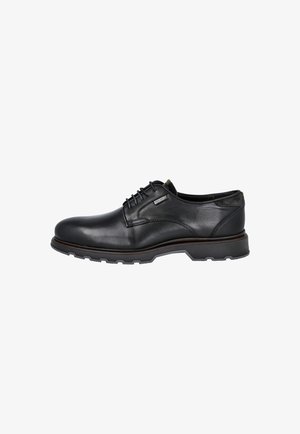 Zapato de vestir masculino de cuero negro con cordones, suela gruesa de goma y pequeña etiqueta con logo en el lateral, sobre fondo blanco.