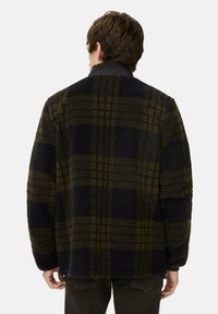 Fleecejacke in dunklem Marineblau und olivgrünem Karomuster mit einem hohen Kragen und plüschiger Textur. Verfügt über heruntergesetzte Schultern und eine lockere Passform.