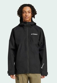 Sort vandtæt jakke med hætte, fuld lynlås og "TERREX" logo. Har GORE-TEX branding på ærmet og justerbare manchetter.
