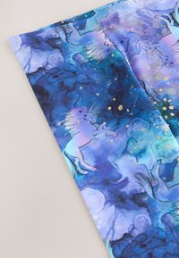 Blått tyg med en akvarelldesign som föreställer enhörningar och guldaccents, med en blandning av lila och teal nyanser.