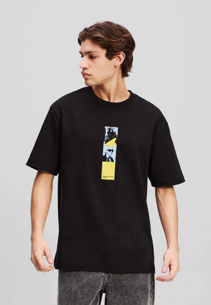 Svart bomulls t-skjorte med et sentralt grafisk design i blått og gult, rektangulær form, med korte ermer og rund hals.