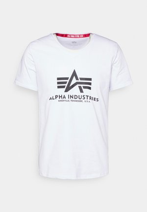 Bijela pamučna majica s V-izrezom i kratkim rukavima. Ima crni grafički logo i natpis "ALPHA INDUSTRIES KNOXVILLE, TENNESSEE, U.S.A."