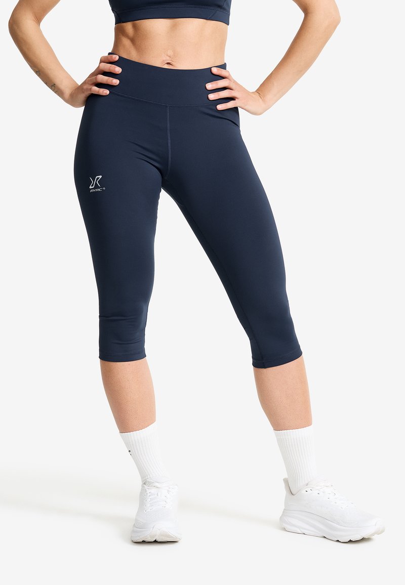 Navy blue capri leggings made from stretchy fabric feature a high waistband and a small logo detail on the left thigh.