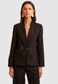 Zwarte pinstriped blazer met een geknipt revers, sluiting met één knop en twee voorzakken. Textuurstof met een getailleerde pasvorm.
