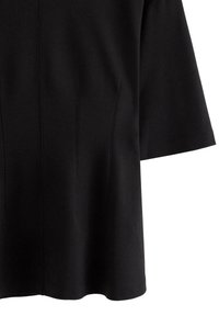 Top nero a maniche corte con taglio dritto, caratterizzato da una sottile texture e dettagli a cuciture verticali per la struttura. Finitura del tessuto liscia.