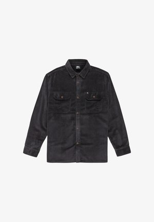 Camisa de pana negra con cuello, cierre de botones y dos bolsillos en el pecho. Presenta una textura acanalada y botones marrones.