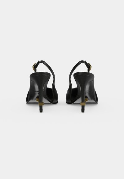 Black high-heeled slingback shoes with thin heels and gold buckle and heel tip details, shown from the back on a white background.