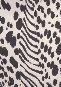 Čierno-biela látka s potlačou zvieracích vzorov, ktorá zobrazuje nepravidelné škvrny a pruhy na textúrovanom pozadí, vytvárajúca odvážny, kontrastný dizajn.