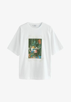 Valkoinen puuvillapaita, jossa on suuri kukkakuosi vihreinä ja pastellisävyinä, ja jossa on sana "Revival" kehystettynä koristeellisella yksityiskohdalla.