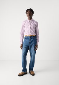 Camisa de rayas de manga larga en rosa y blanco, jeans de mezclilla azul y zapatos sin cordones beige con suelas negras. Textura natural y ajuste casual.