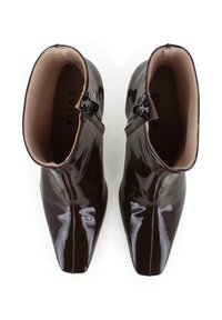 Stivali alla caviglia in pelle patent marrone con punta affusolata, chiusura con zip sul lato e finitura liscia e lucida. L'interno presenta una fodera beige.