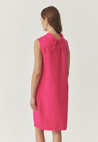 Mouwloze roze linnen jurk met een grote kraag en een keyhole-detail aan de achterkant, met een rechte snit en een knie-lange ontwerp.